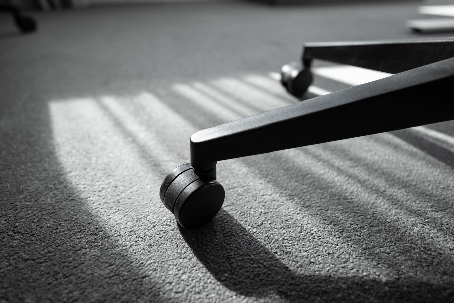 närbild på foten av en kontorsstol mot en heltäckningsmatta