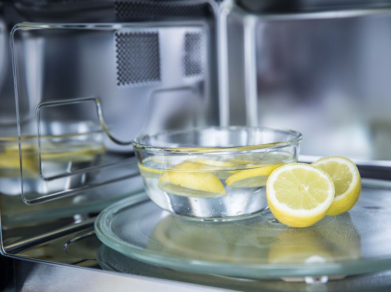 En skål med vatten och skivade citroner i en mikrougn