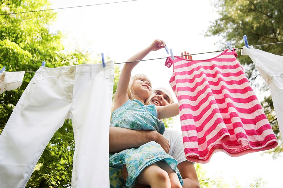 Barn hänger upp nytvättade kläder på tork