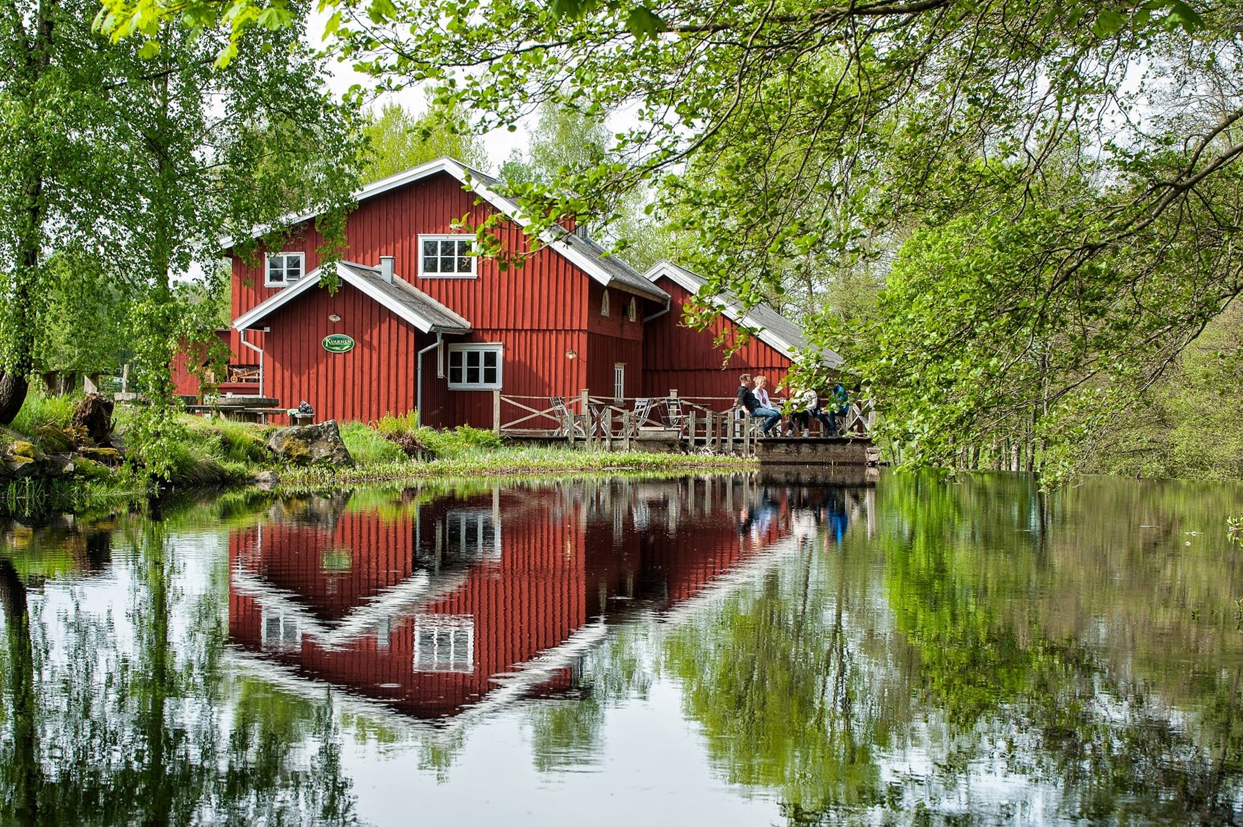 Några folk sitter på bryggan vid den röda kvarnen i Hyssna