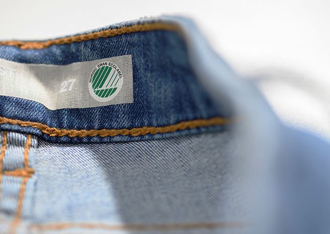 Närbild på Svanenmärkta jeans med tydlig Nordic Swan Ecolabel logo