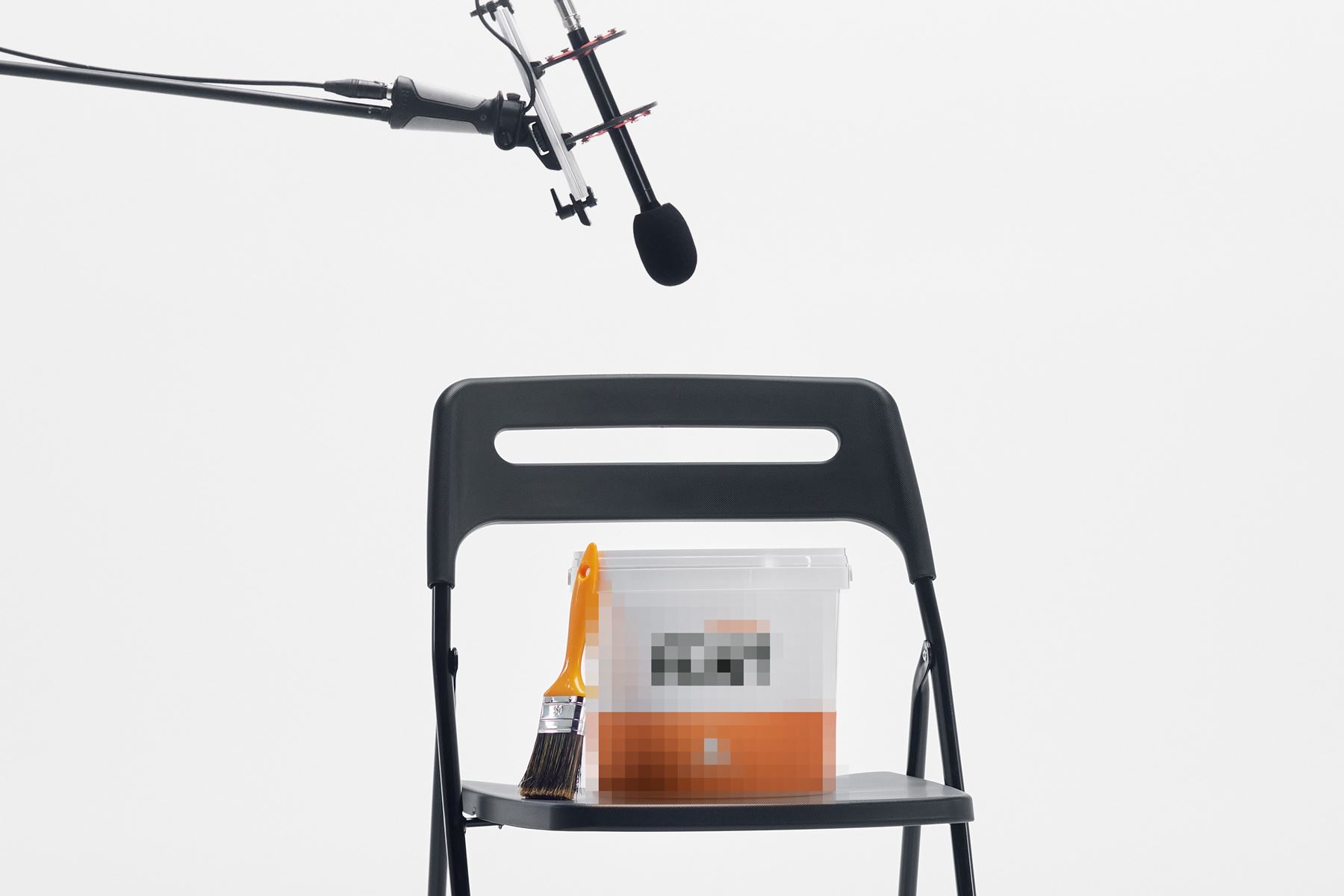 Suddig anonym målarfärgburk på en stol med en mikron ovanför riktad mot sig som att den blir intervjuad.