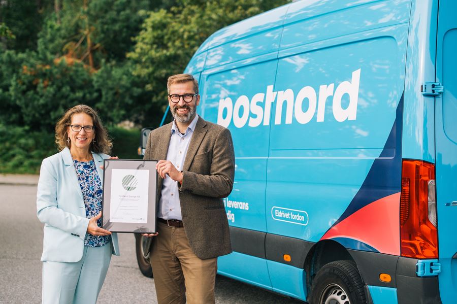 Svanens vd Anna Linusson och Mathias Krümmel, vd Postnord Sverige står framför en PostNord-bil och håller i ett certifigat för Svanenmärkning av e-handelstransporter.
